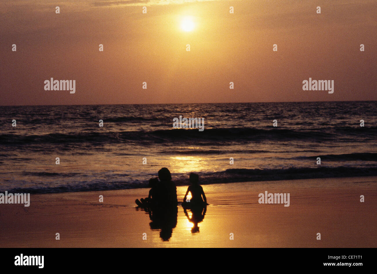 SOA 82486: Silhouette des Mutter-Tochter sitzen bei Sonnenuntergang am Strand von Salcete; Goa; Indien Stockfoto