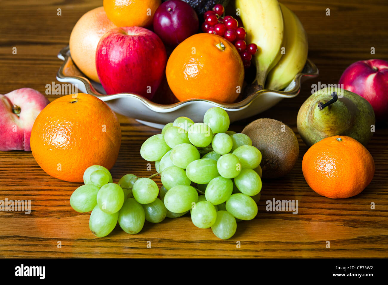 Auswahl an bunten, frischen, natürlichen aussehende Frucht in eine alte Schüssel platziert auf Holz. Stockfoto