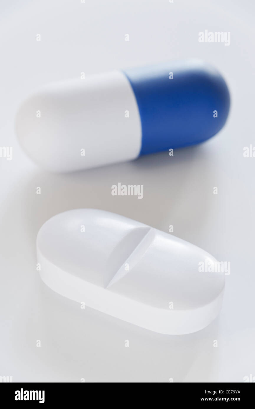 Eine weiße Tablette und eine blau-weiße Kapsel auf weißem Hintergrund Stockfoto
