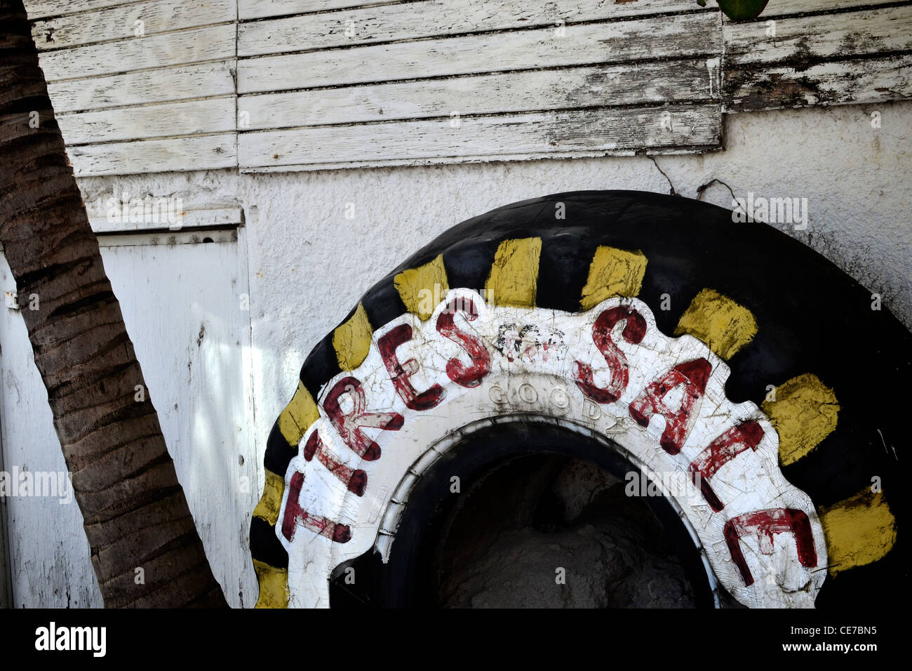 Reifen an der weißen Wand angelehnt. Kommerzielles Zeichen für einen kleinen Reifenverkauf in Saint Martin, Karibik. Stockfoto