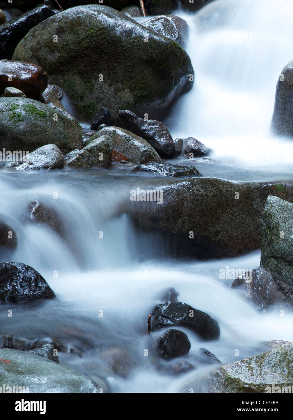 Wasserfälle fließen über Flussfelsen, frisches Bergstromwasser, das bei langer Belichtung angeschossen wird, sorgt für ein weiches, meditatives Gefühl Stockfoto