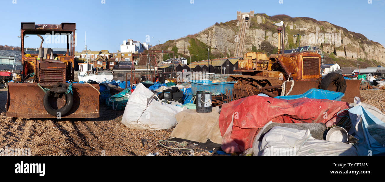 Fischerei-Industrie am Strand in Hastings. Traktor oder Bagger mit Landwirtschaftsausrüstung und Stadt im Hintergrund Stockfoto