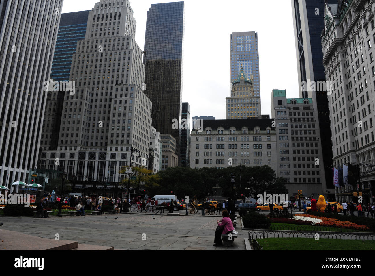 Grauen Himmel Blick Leute sitzen essende Steinbänken Grand Army Plaza, in Richtung West 59th Street 5th Avenue Wolkenkratzer, New York Stockfoto