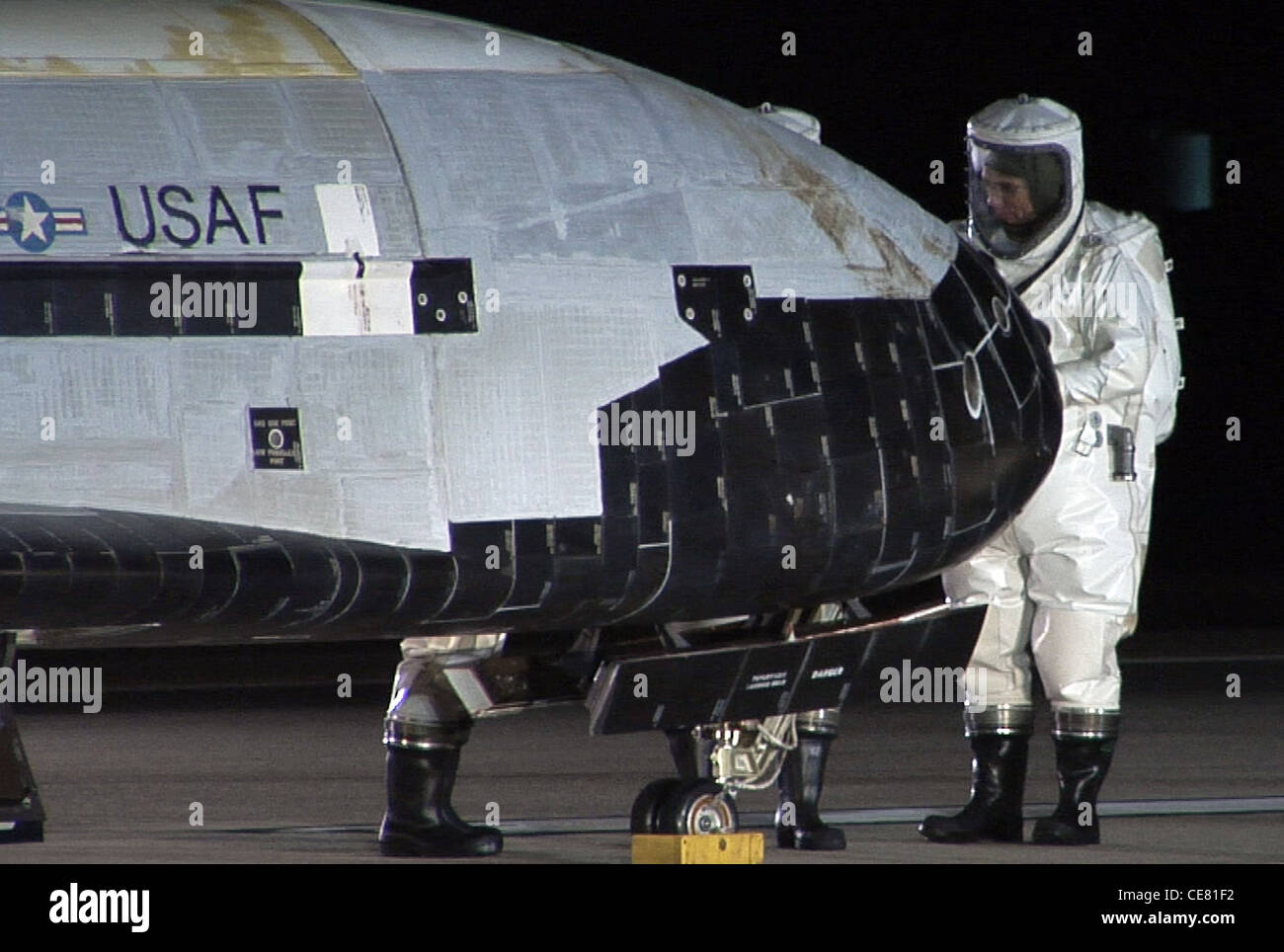 Techniker in geschlossenen atmosphärischen Schutzanzügen führen erste Kontrollen am X-37B Orbital Test Vehicle 1) nach seiner Landung am 3. Dezember 2010 auf der Vandenberg Air Force Base, Kalifornien durch. Dies ist das erste unbemannte Wiedereinstieg-Raumschiff der Air Force. Stockfoto