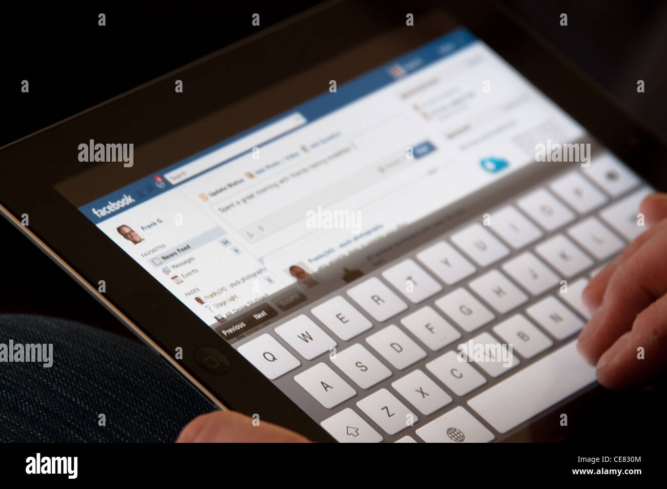 Nahaufnahme von einem Apple-iPad-Bildschirm zeigt die Facebook-Website mit zwei männlichen Händen tippen ein Status-update Stockfoto