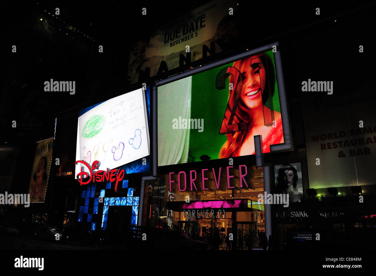Nacht Sicht Menschen, Verkehr, Neon Fassaden LED Bildschirme, Disney Store, weibliche Modellbild Forever 21 Boutique, 7th Avenue, New York Stockfoto