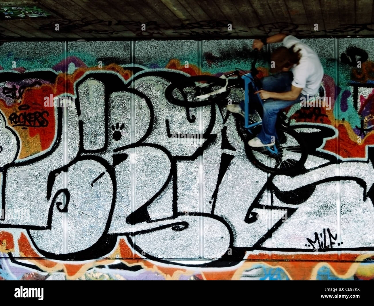 Ein urban Stunt Radfahrer springt durch die Luft, vor dem Hintergrund der Graffiti verziert. Stockfoto