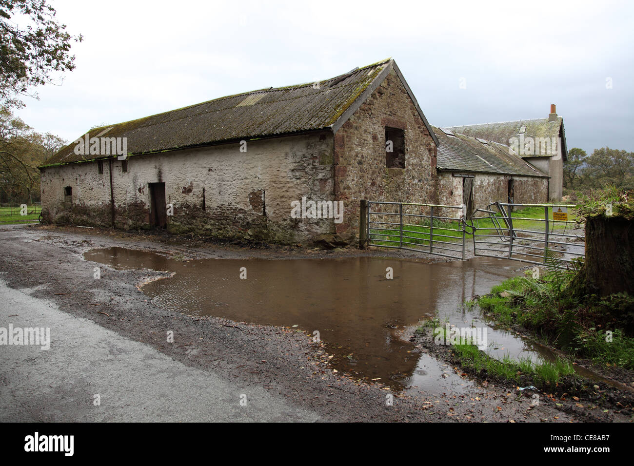 traditionelles landwirtschaftliches Gebäude zeigen, Überflutung von Straßen und schlechte Entwässerung nach Starkregen Stockfoto