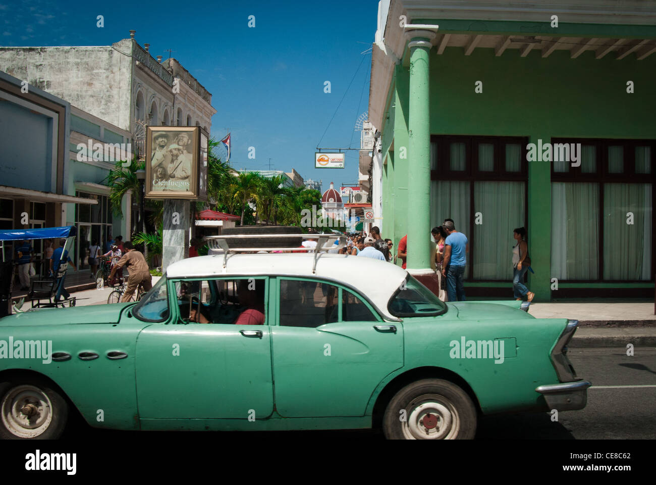 Amerikanische Oldtimer, Blick in eine Bulevard im Hintergrund und ein Plakat Werbung für live-Musik in Cienfuegos Stockfoto