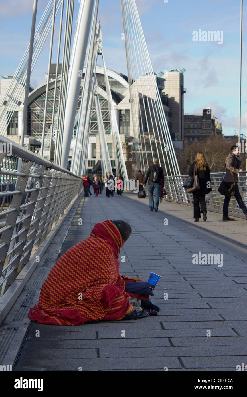 Mann eingewickelt in Decke Betteln auf Golden Jubilee Bridge, London, UK Stockfoto