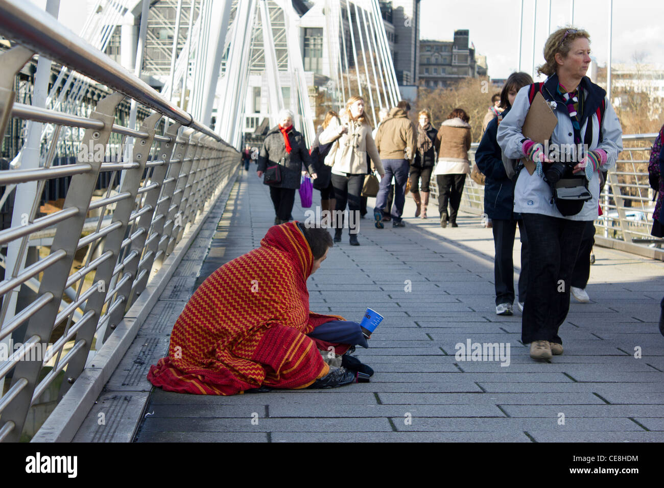 Mann eingewickelt in Decke Betteln auf Golden Jubilee Bridge, London, UK Stockfoto