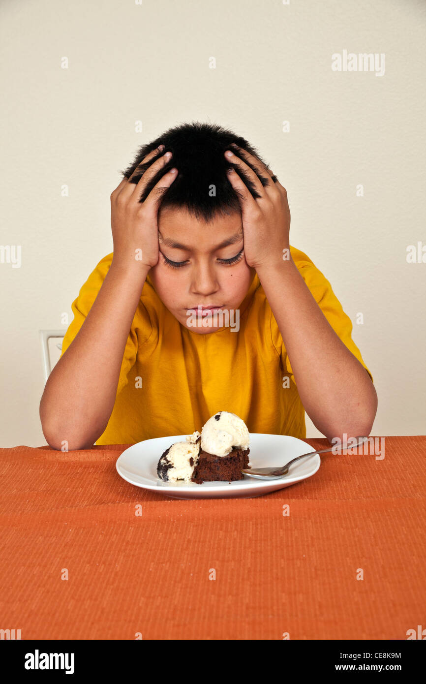 Willensstark hartnäckige 10-11 Jahre alten Hispanic junge am Tisch sitzen will nicht essen. Multi ethnische Vielfalt ethnisch vielfältigen multikulturellen cultura Stockfoto