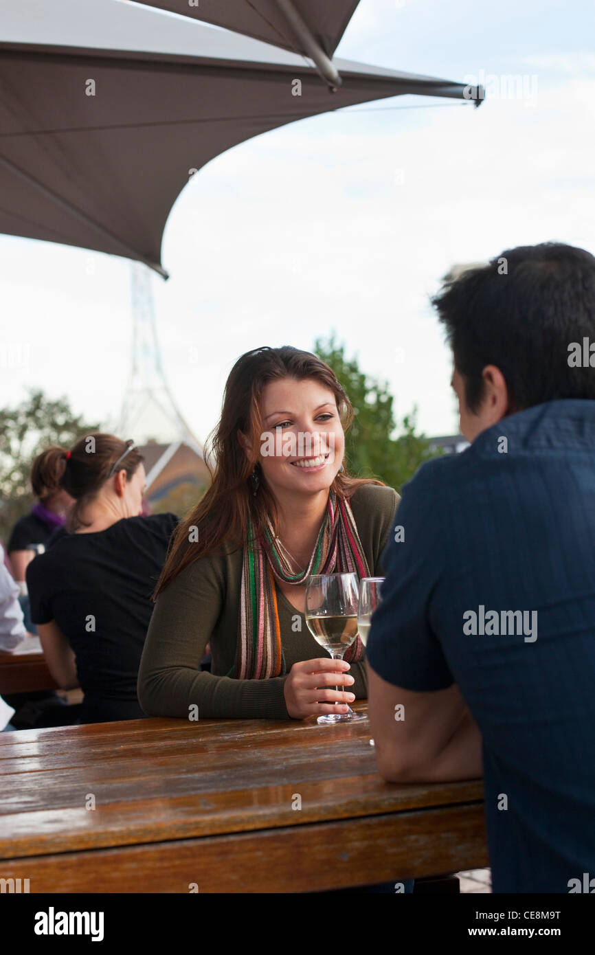 Junges Paar Drink an einer Bar im Freien genießen. Federation Square, Melbourne, Victoria, Australien Stockfoto
