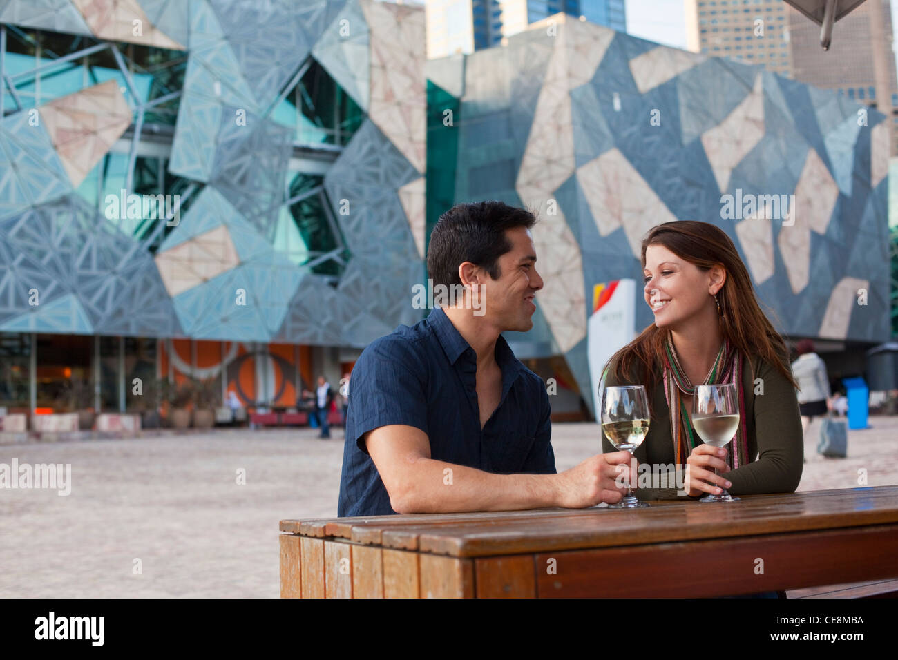 Junges Paar Drink an einer Bar im Freien genießen. Federation Square, Melbourne, Victoria, Australien Stockfoto
