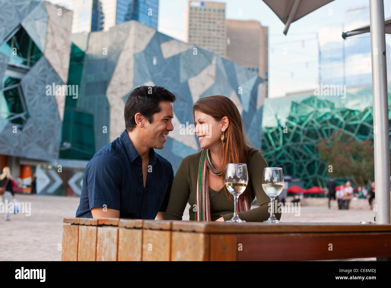 Junges Paar Drink an einer Bar im Freien genießen. Federation Square, Melbourne, Victoria, Australien Stockfoto