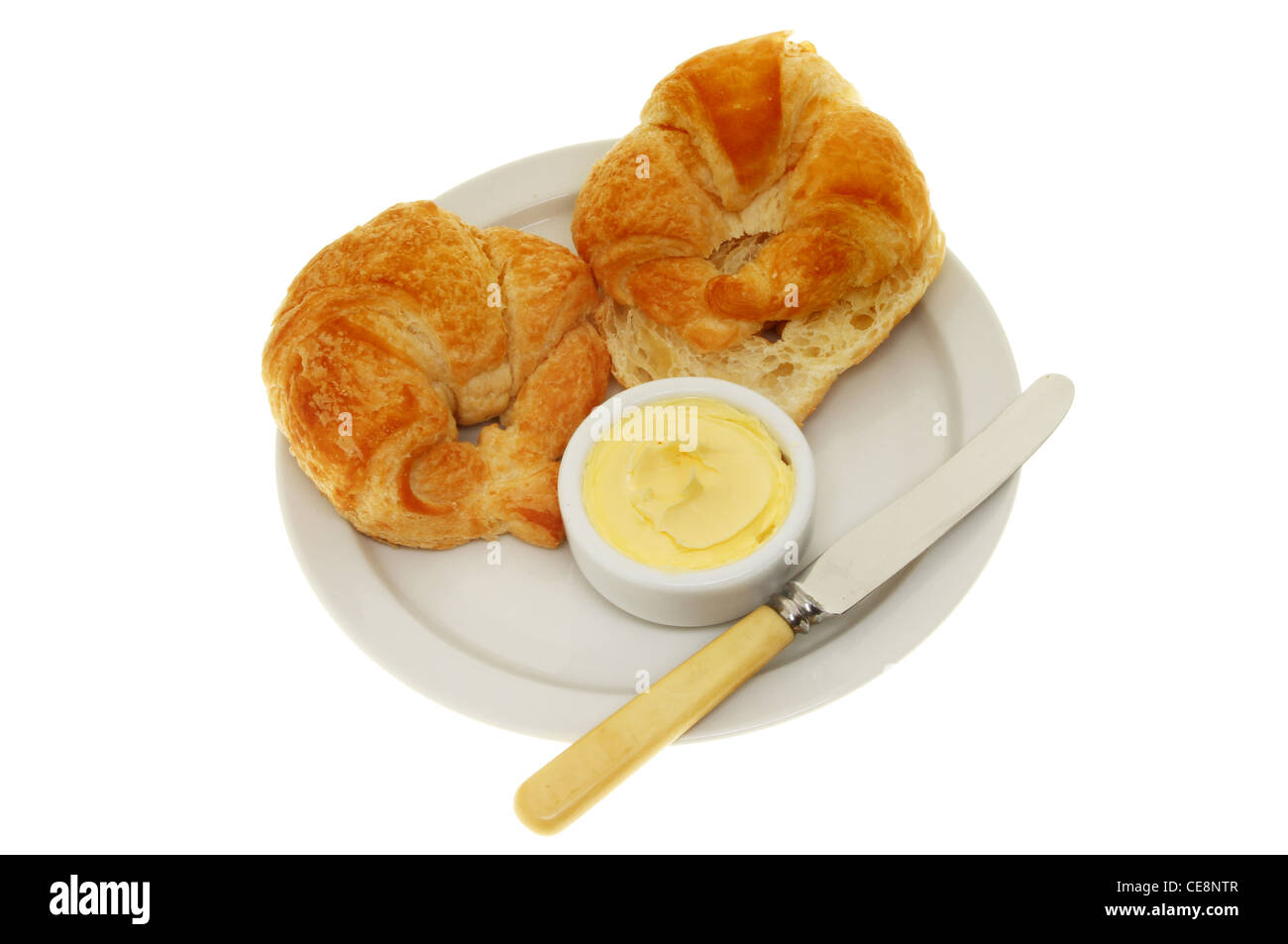 Zwei Croissants, Butter und ein Messer auf einem Teller isoliert gegen weiß Stockfoto