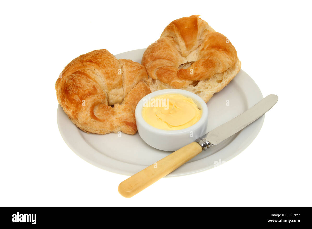 Croissants, Butter und ein Messer auf einem Teller isoliert gegen weiß Stockfoto
