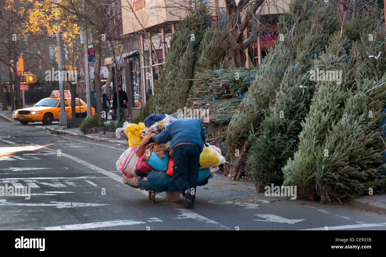 Obdachlose Menschen drängen Trolley mit seinen Habseligkeiten durch niedrigere Manhattan Straßen zur Weihnachtszeit Stockfoto