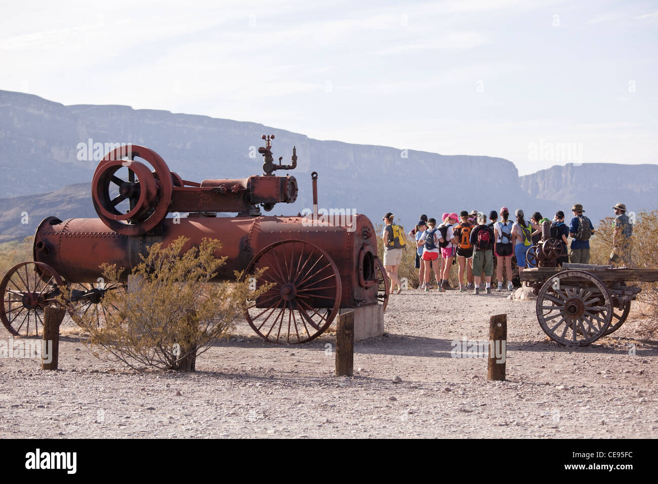 Eine alte Dampfmaschine und Wagen sitzen am Castolon, TX in Big Bend Nationalpark als eine Gruppe von Schule Kinder Blick auf die westlichen vista Stockfoto