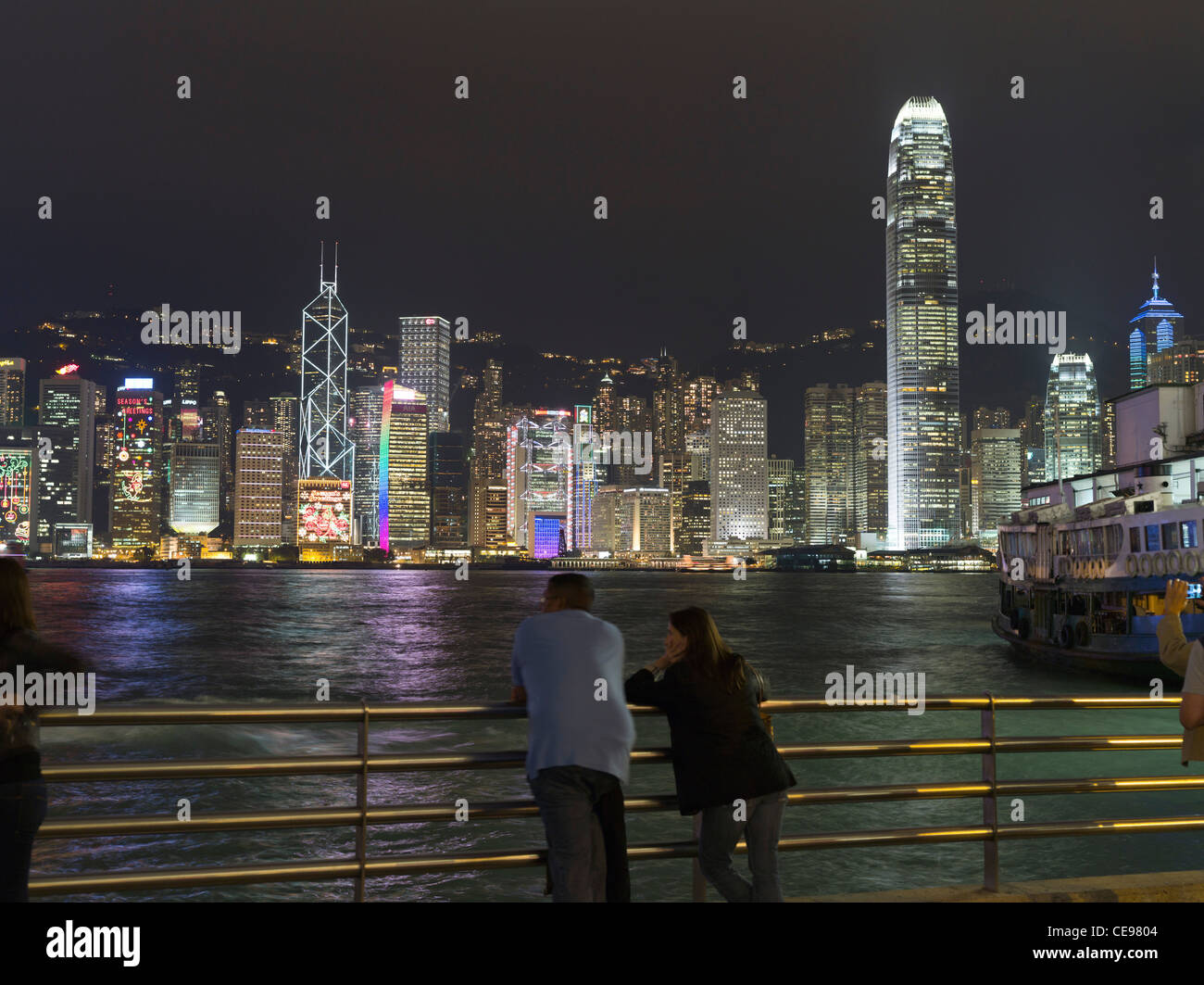 dh Hong Kong Harbour TSIM SHA TSUI HONG KONG Paar in Kowloon Waterfront Nachtlichter Menschen Blick Stockfoto
