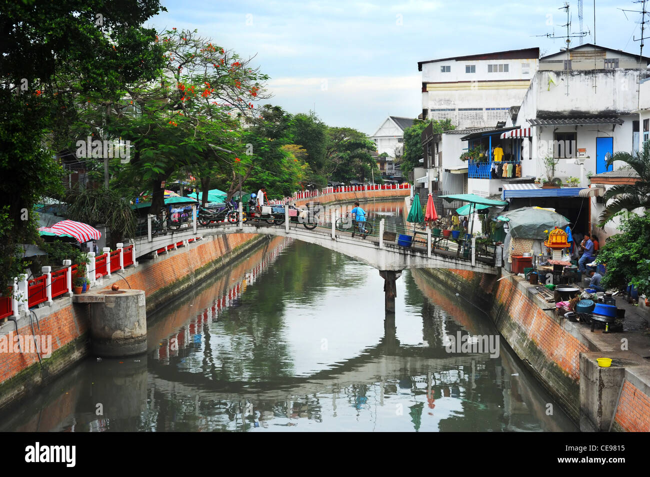 Menschen zu Fuß mit dem Fahrrad auf der kleinen Brücke über den Kanal in Bangkok slum Stockfoto