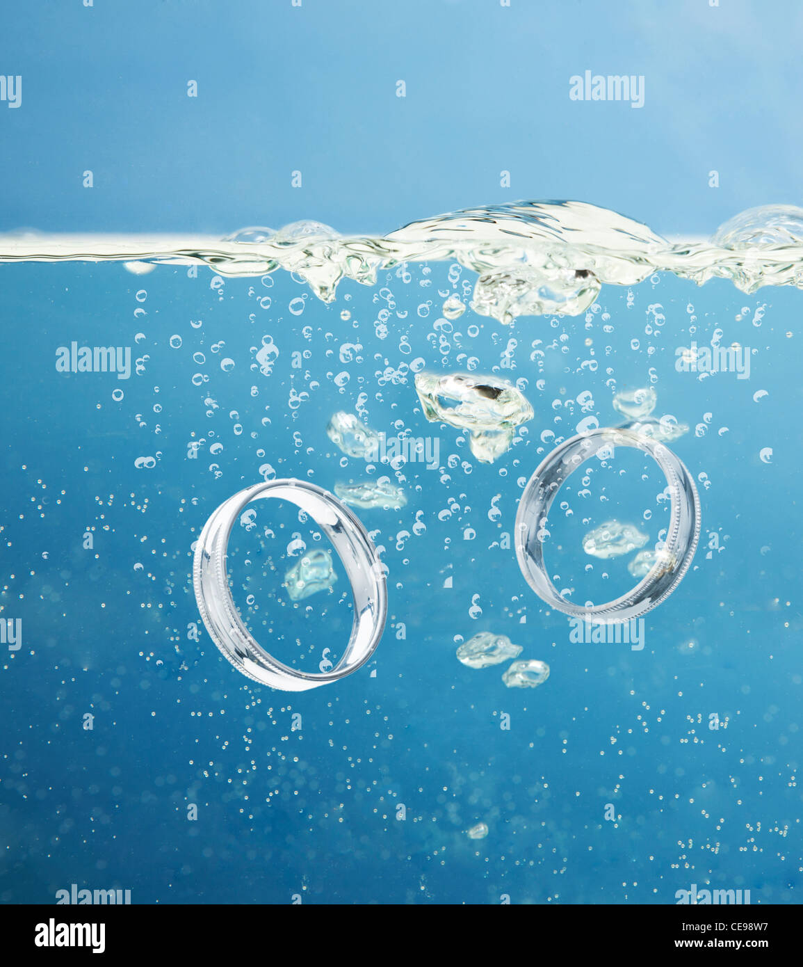 Studioaufnahme von Silber Trauringe ins Wasser fallen Stockfoto