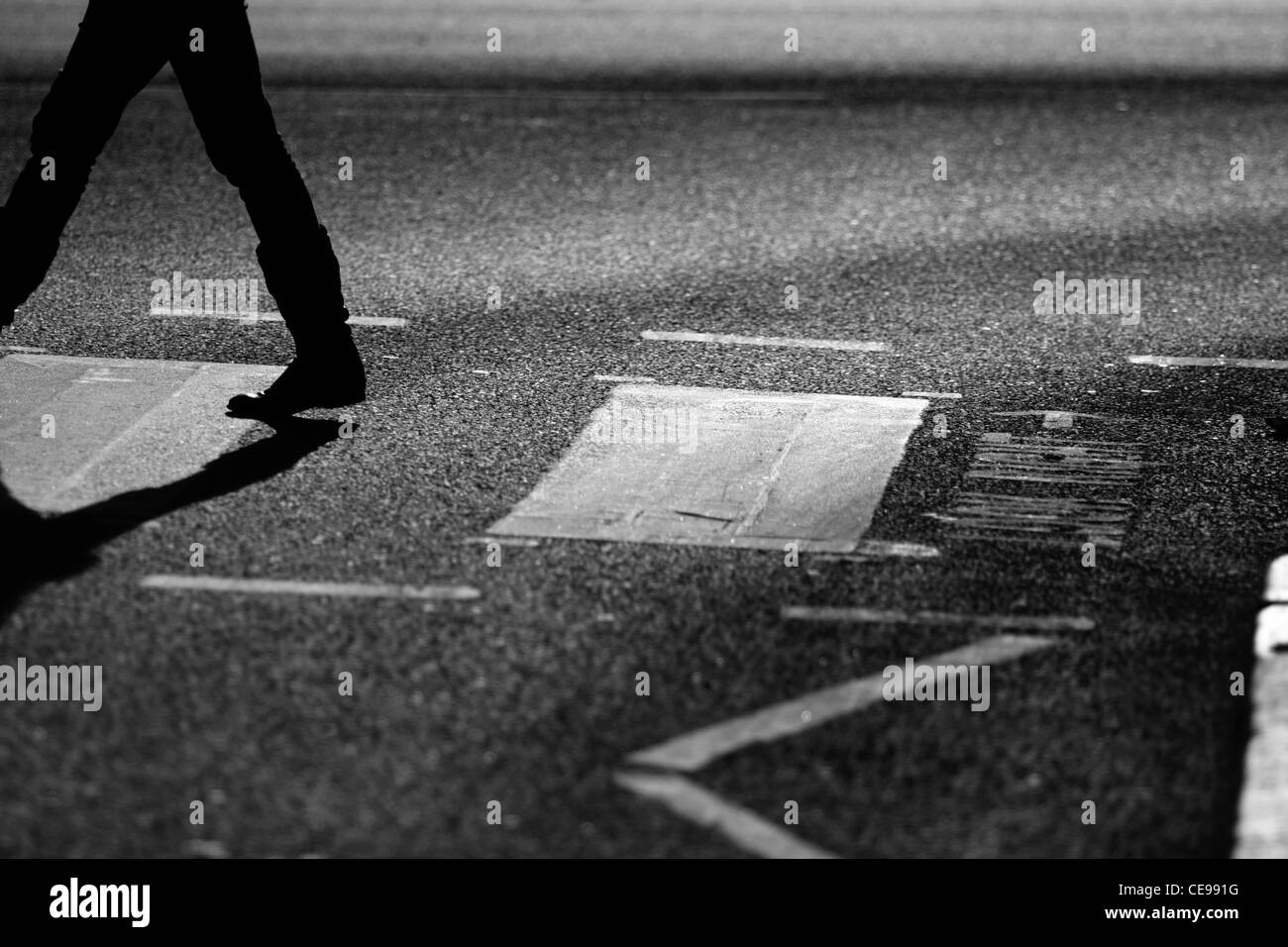 Die Beine einer Person als sie überqueren eine Straße auf einem Zebrastreifen in London Stockfoto