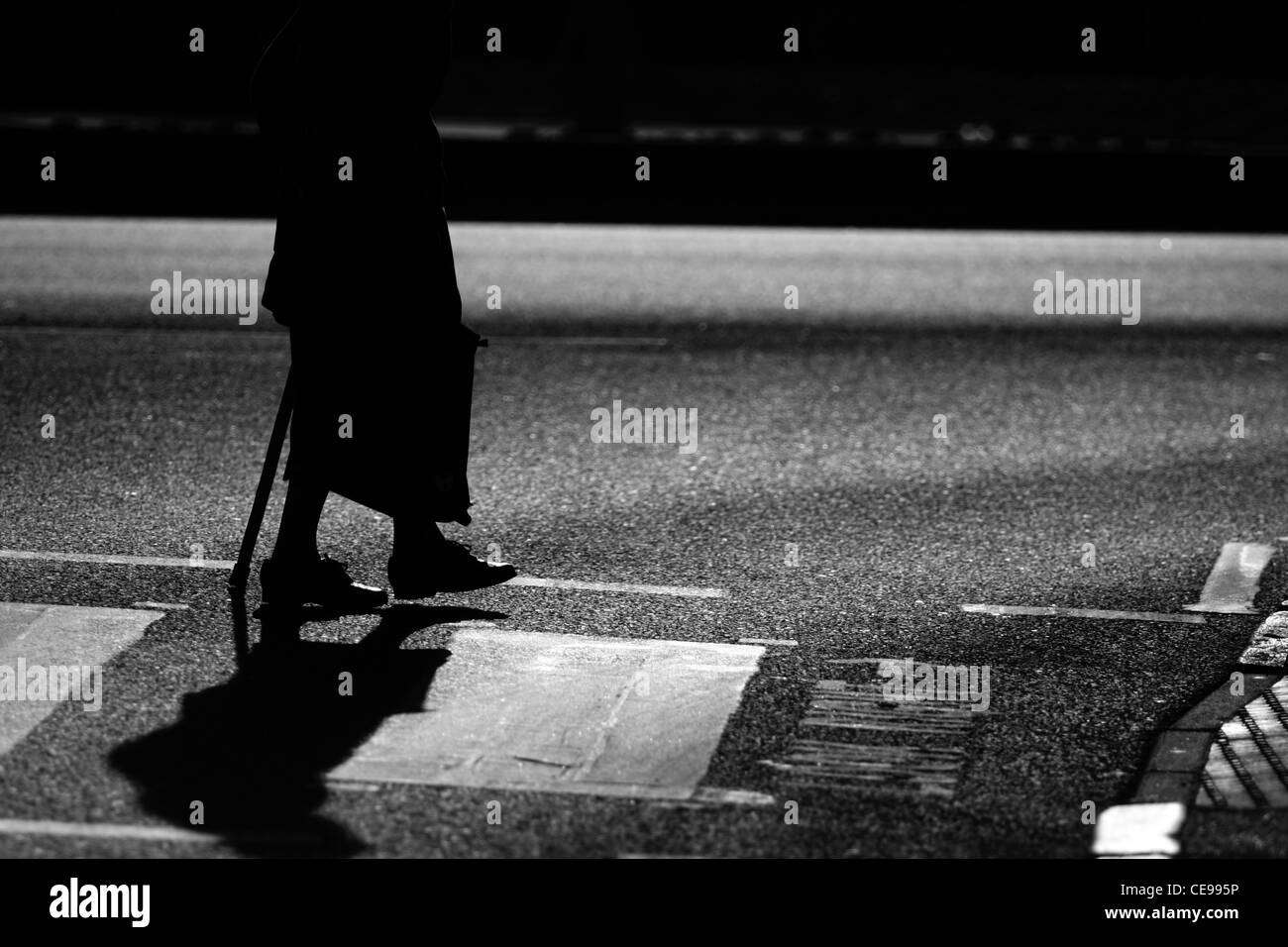 Eine ältere Dame überqueren einer Straße an einem Zebrastreifen in London Stockfoto