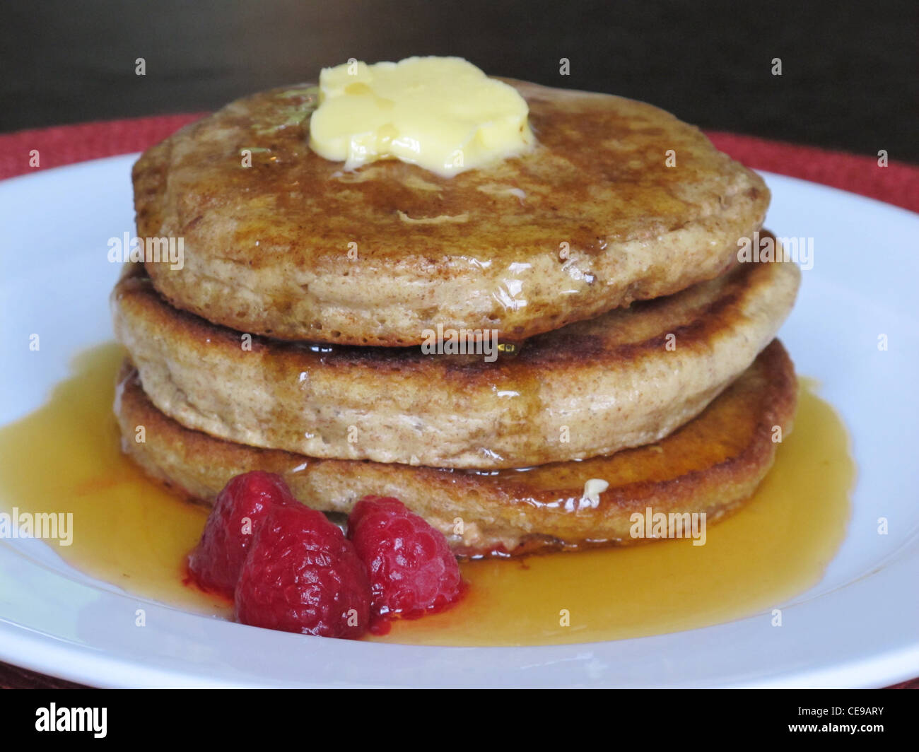 Einen leckeren Pfannkuchen mit Ahornsirup und Butter, mit Himbeeren auf der Seite.  Das Frühstück hat hohen Kaloriengehalt. Stockfoto