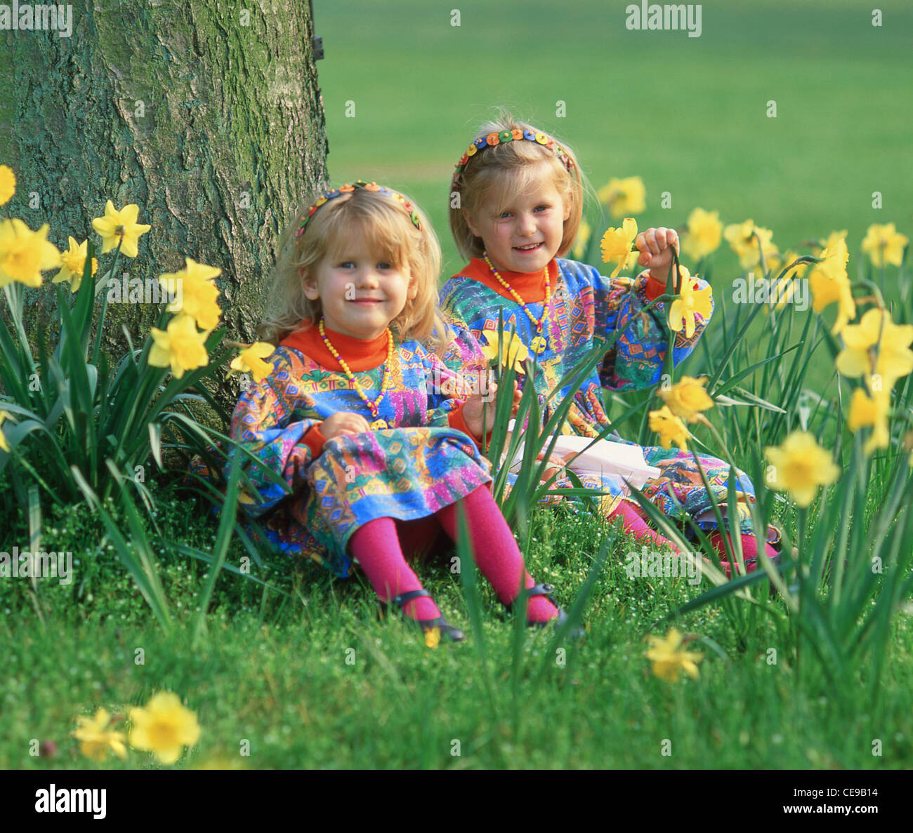 Junge Mädchen, die im Frühjahr auf dem Feld der Narzissen sitzen, Berkshire, England, Großbritannien Stockfoto