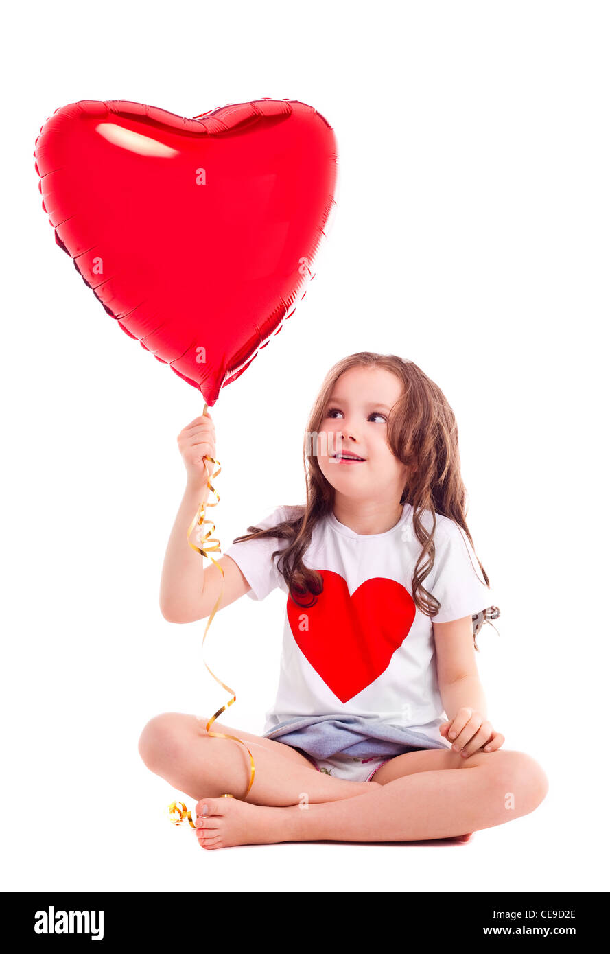 niedliche sechs Jahre alten Mädchen trägt ein T-shirt mit einem großen roten Herz auf weißen Hintergrund isoliert Stockfoto