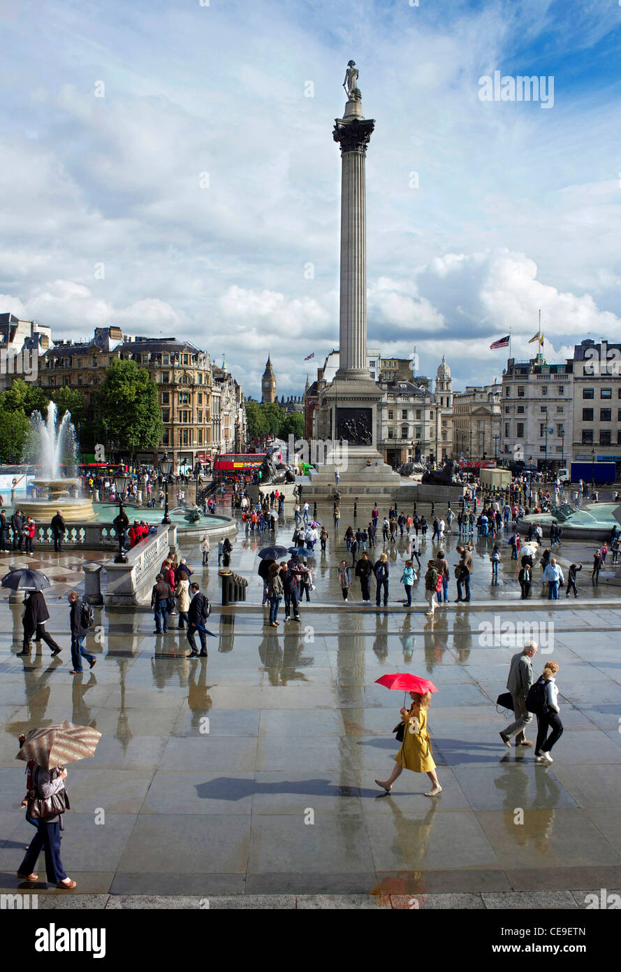 Menschen immer noch mit Sonnenschirmen im Regen, als die Sonne beginnt zu leuchten auf dem Trafalgar Square, London, England. Stockfoto