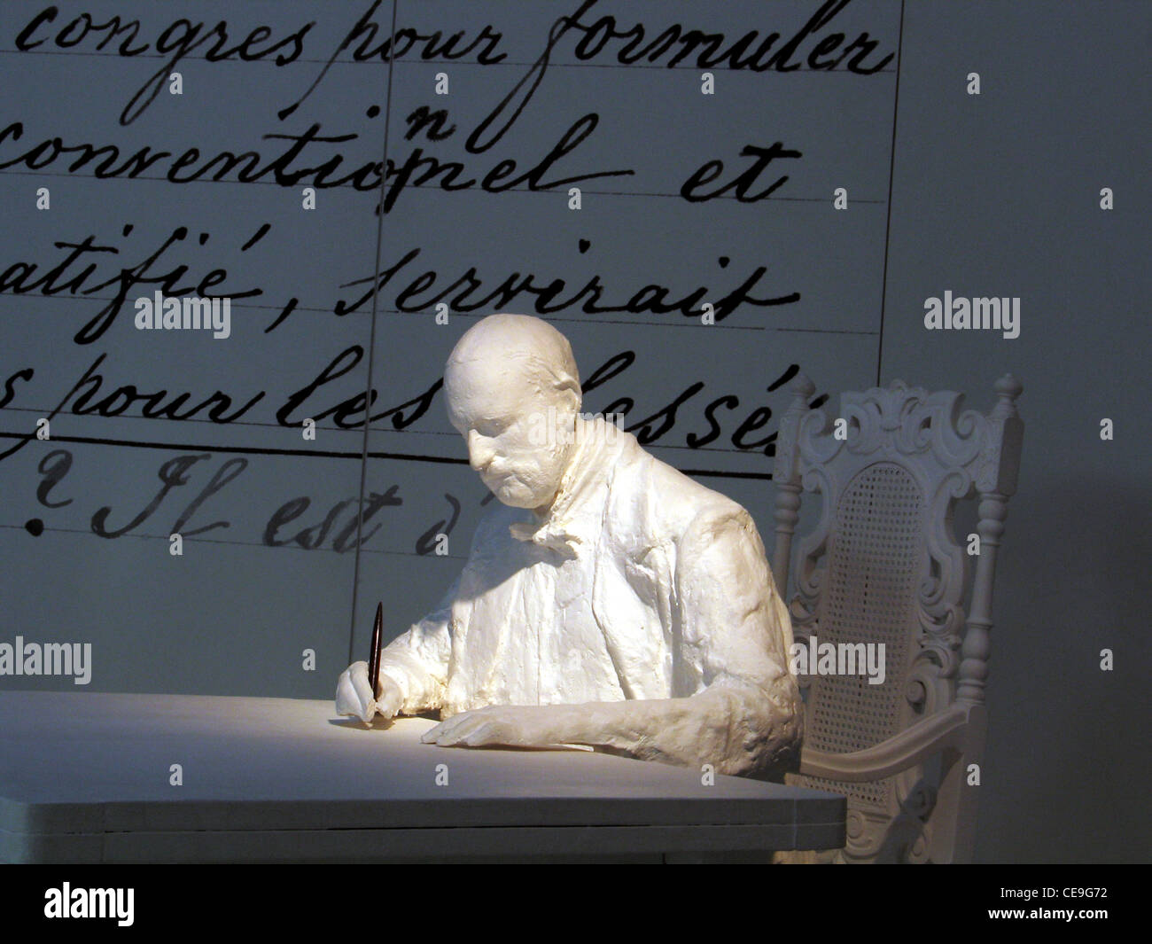 Statue von Jean Henry Dunant 1828 1910 Schweizer Philanthropen und Friedensnobelpreisträger, der auch das Rote Kreuz gründete, sitzend vor seinen Ideen Handschrift über die Schaffung eines Freiwilligenkomitees zur Versorgung von Kriegsverwundeten, bekannt als das Buch A Memory of Solferino, das bei der International ausgestellt wurde das Rote Kreuz- und Rothalbmondmuseum bietet detaillierte fotografische und andere physische Beweise für den Dienst des IKRK an der Menschheit während zahlloser Kriege und Naturkatastrophen in Genf, Schweiz Stockfoto