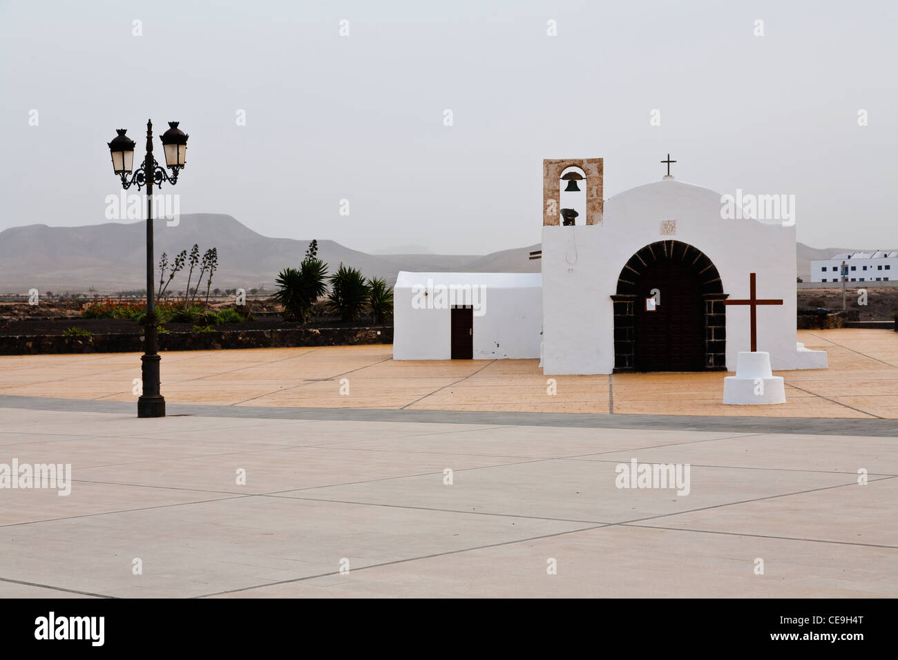 Eine kleine Kirche mit einem Kreuz und Lamp Post im Vordergrund. El Cotillo, Fuerteventura, Spanien. Stockfoto