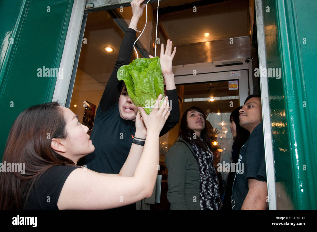 Chinesischen Brauch, hängende Salat in Tür des Restaurants für die Marionette Löwe zusammen mit roten Umschlag mit Geld für Essen gehen Stockfoto