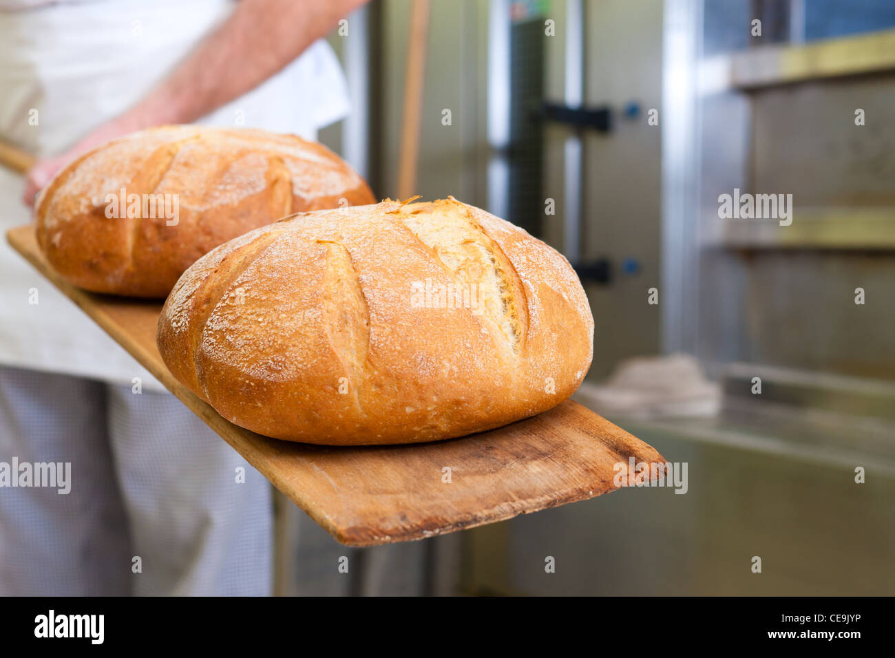 Männliche Bäcker backen frisches Brot in der Backstube Stockfoto
