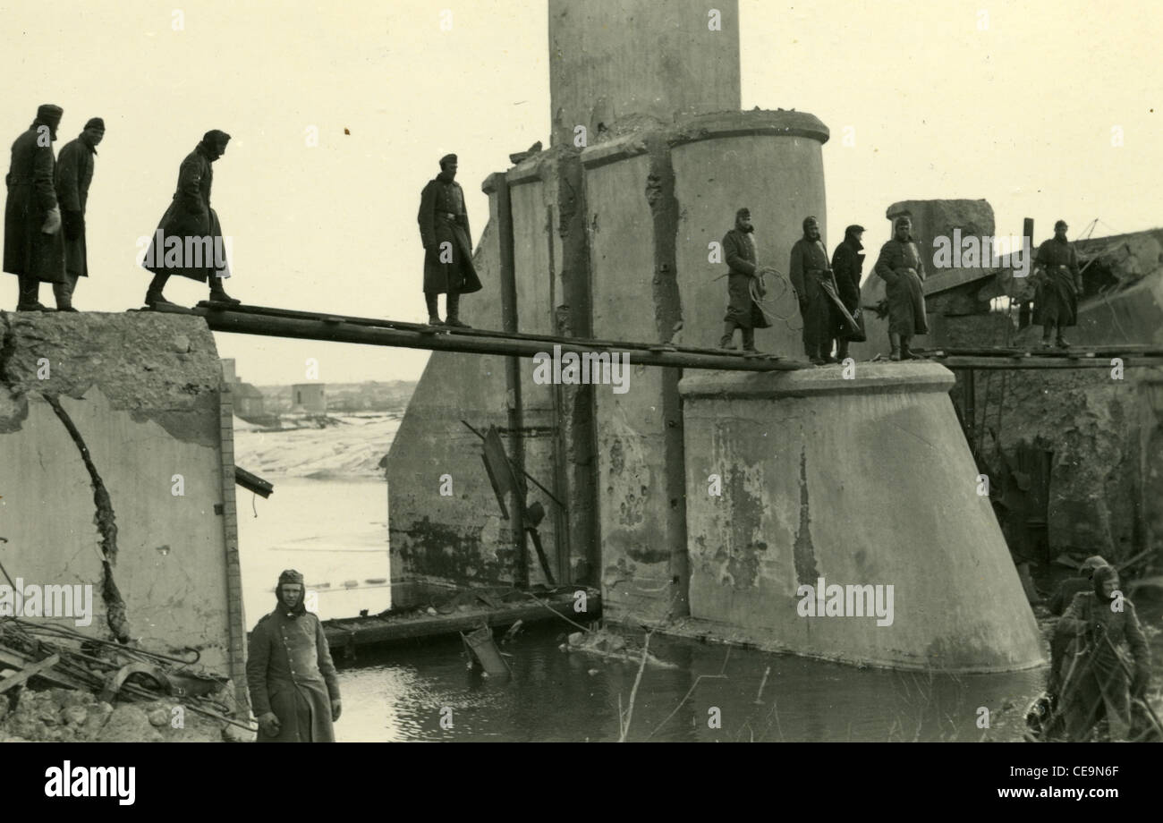 Nazi-deutschen Soldaten gekleidet in Trenchcoats Kreuz Plank auf bombardiert Brücke über den River Stockfoto