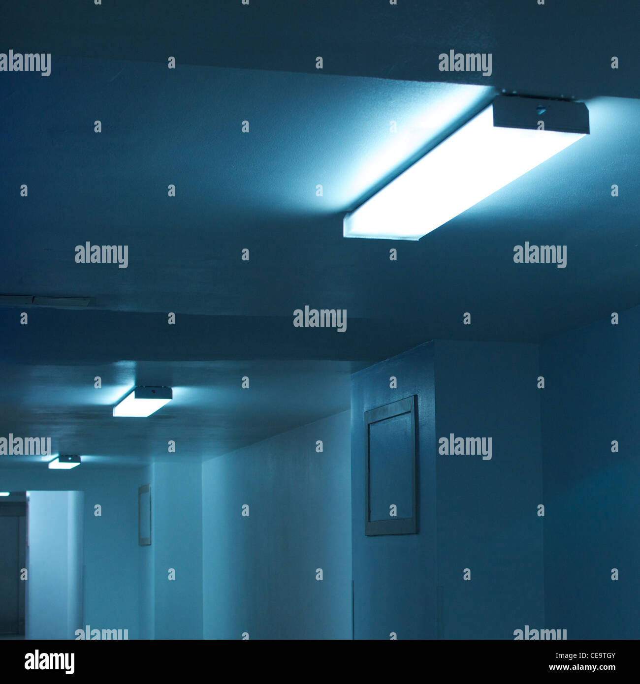 Fluoreszierende Deckenleuchten in unterirdischer Durchfahrt zwischen Gebäuden. Blau, monochrom. Quadratisch. Stockfoto