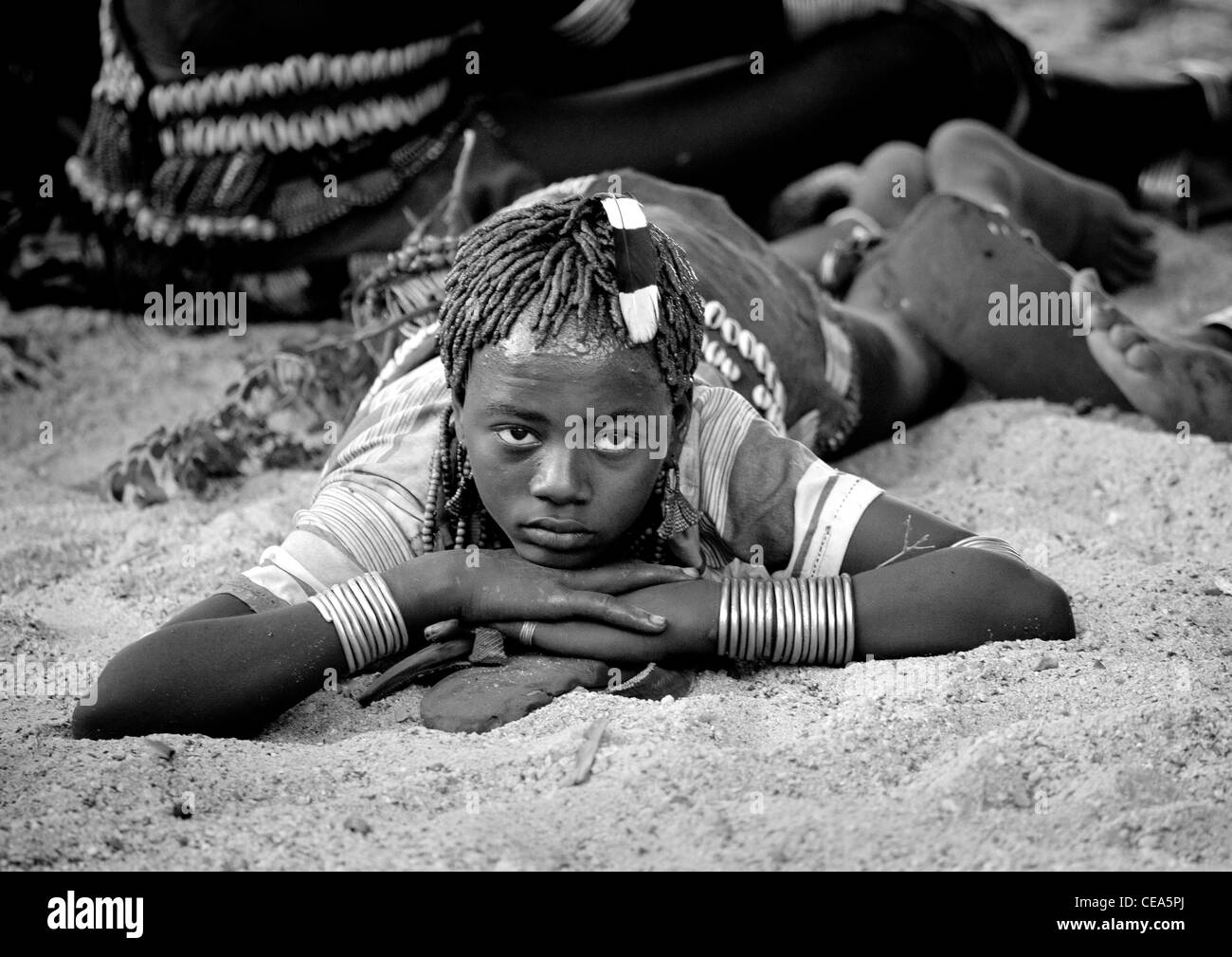 Junge Hamer Frau Verlegung nach unten in den Sand auf ihrem Magen-Äthiopien Stockfoto