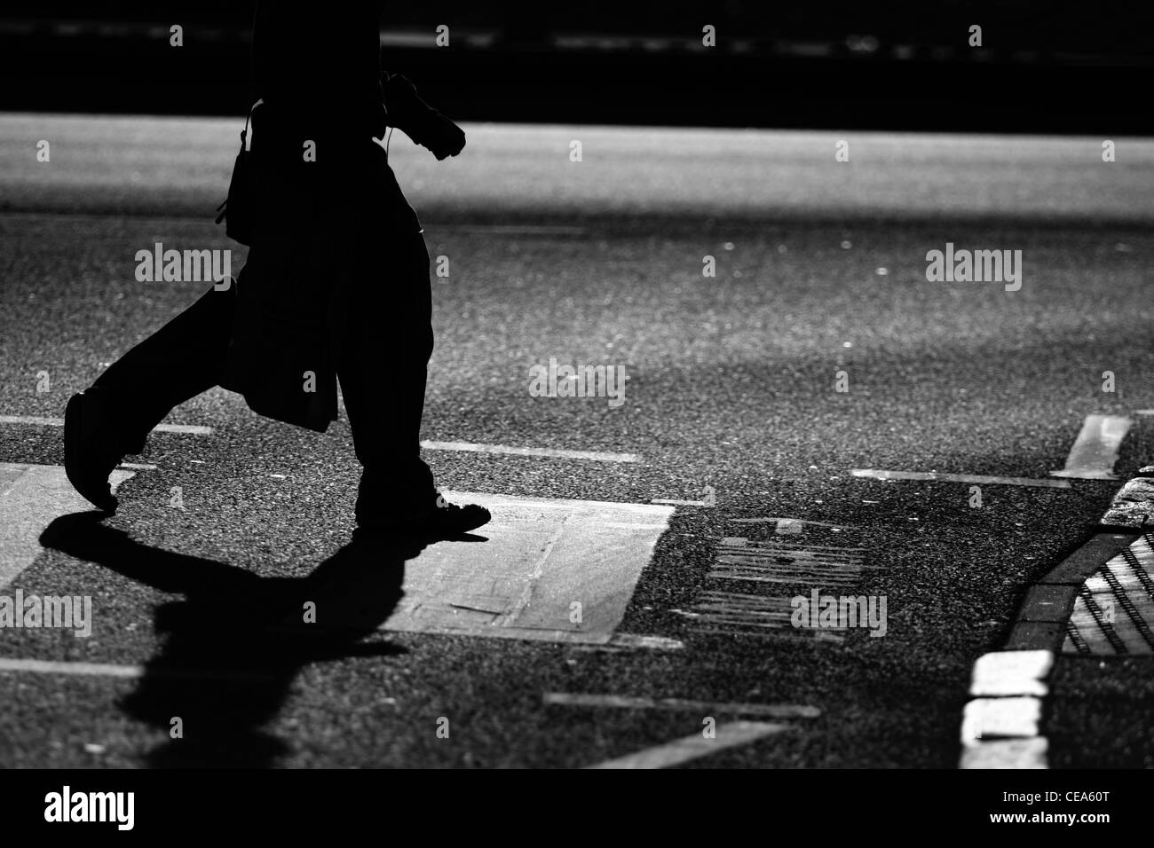Die Beine eines Mannes als er eine Straße auf einem Zebrastreifen in London überquert Stockfoto