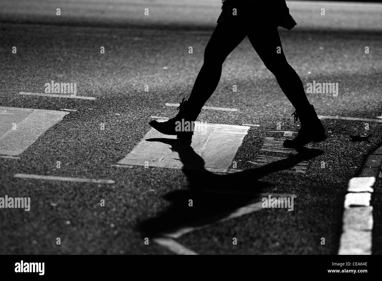 Die Beine eines Mannes als er eine Straße auf einem Zebrastreifen in London überquert Stockfoto