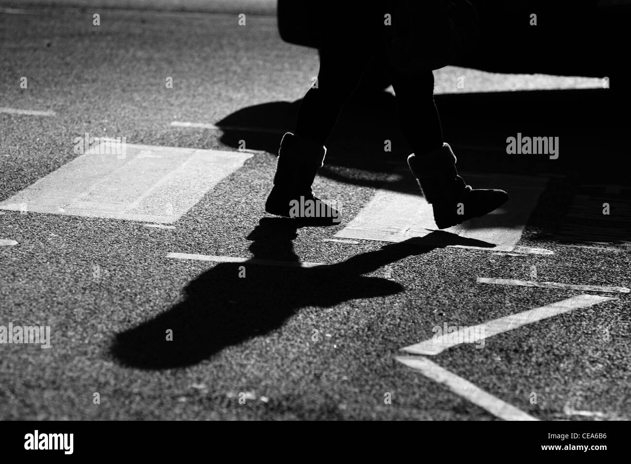 Die Beine einer Frau wie sie eine Straße auf einem Zebrastreifen in London kreuzt Stockfoto