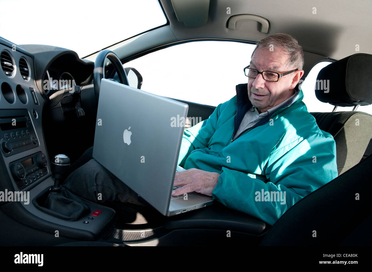 ältere Mann mit Laptop-Computer im Auto Stockfoto