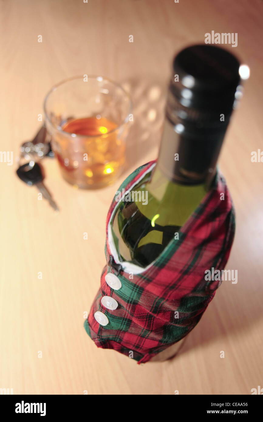 Flasche gekleidet in wärmere Jacke mit Autoschlüssel am Schreibtisch mit Trunkenheit am Steuer und Süchten können tödlich sein Stockfoto