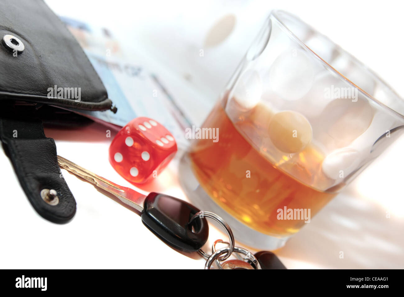 Würfel und Whiskey Glas mit Autoschlüssel und Bargeld auf weißem Hintergrund mit Glücksspiel mit Trunkenheit am Steuer und Süchte kann tödlich sein Stockfoto