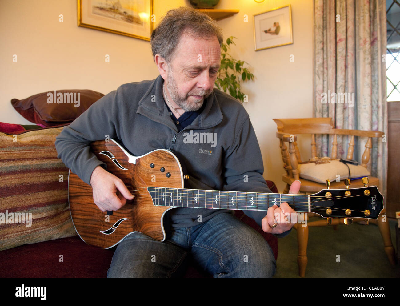 Ein Mann mittleren Alters, spielt akustische Gitarre eine Taylor, UK Stockfoto