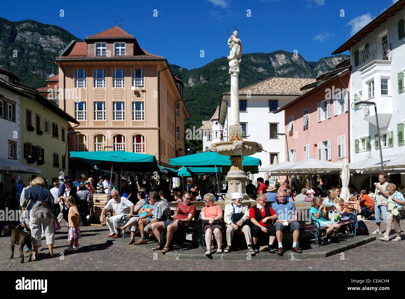 Touristen auf dem Marienbrunnen auf dem Marktplatz von Kaltern an der Südtiroler Weinstraße. Stockfoto