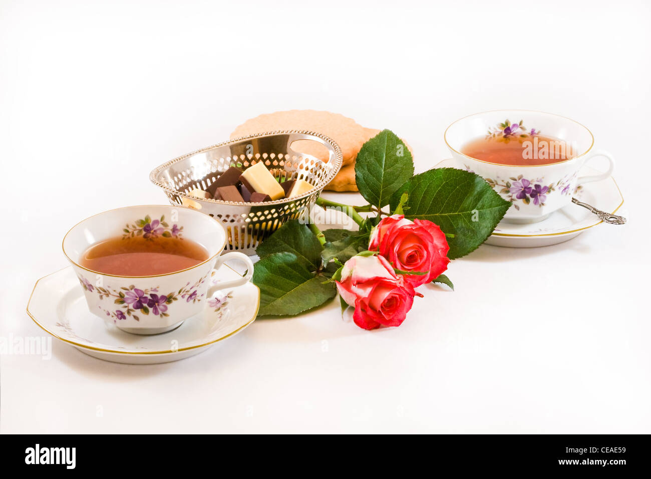 Zwei Tassen Tee mit Schokolade, Plätzchen und rote Rosen auf weißem  Hintergrund Stockfotografie - Alamy