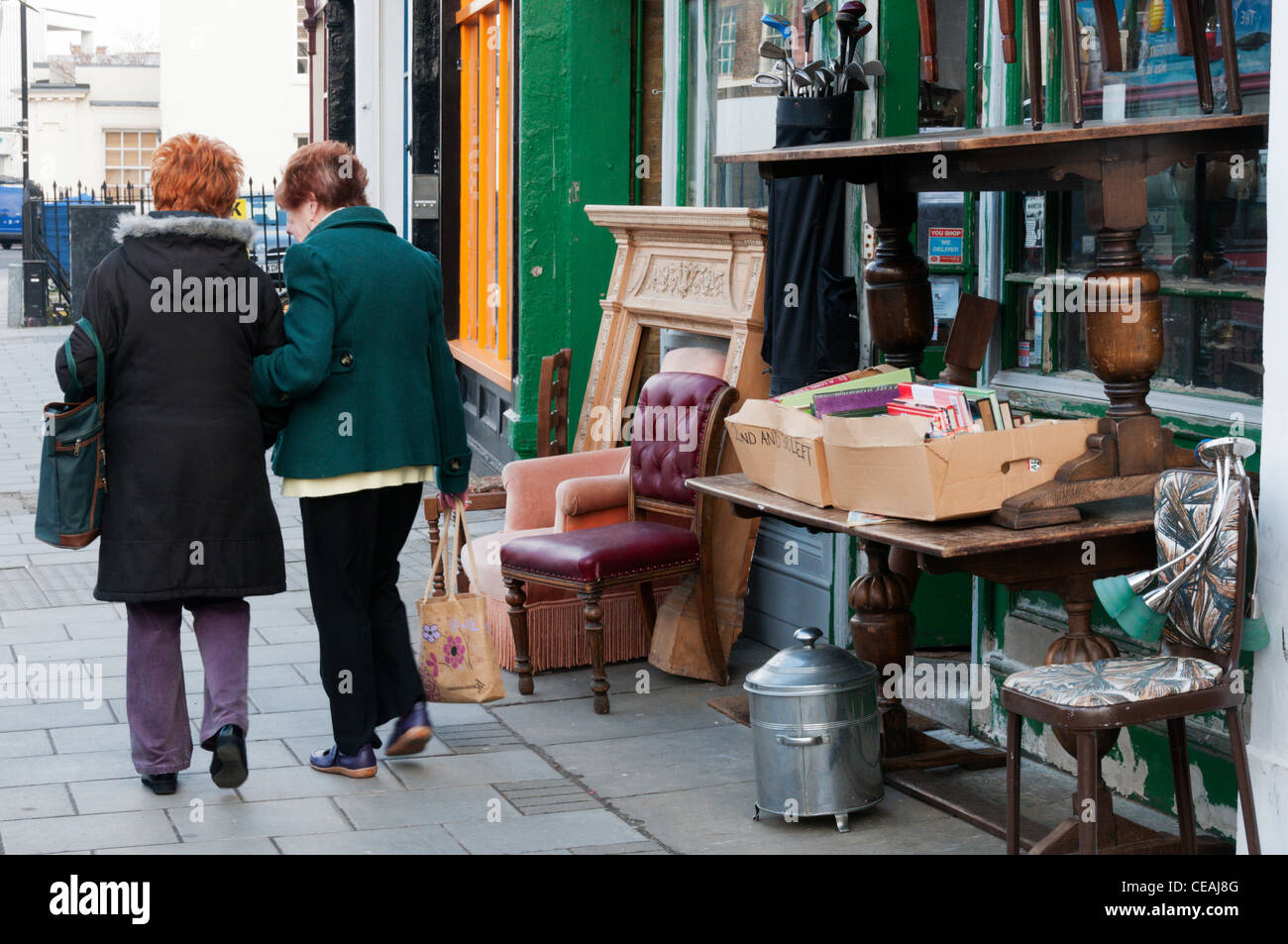 Ein paar ältere Damen Walkiing vorbei an einem Trödelladen in Greenwich, Südlondon. Stockfoto