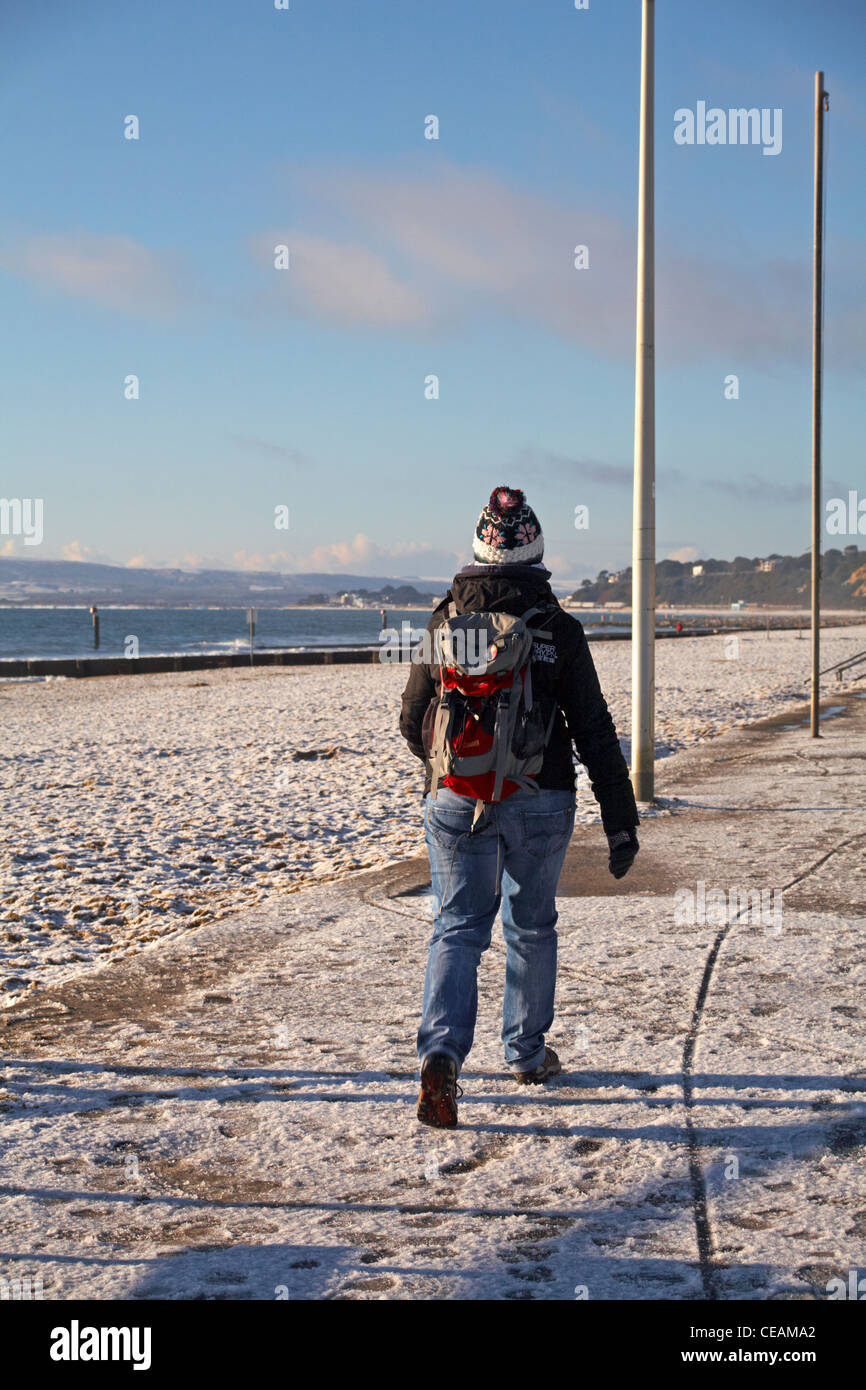 warm zu Fuß entlang der Strandpromenade zwischen Bournemouth und Poole mit Schnee auf dem Boden im Dezember eingewickelt Stockfoto